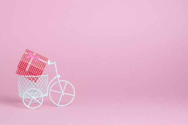 Una bicicleta de juguete lleva un regalo. La idea de una postal.