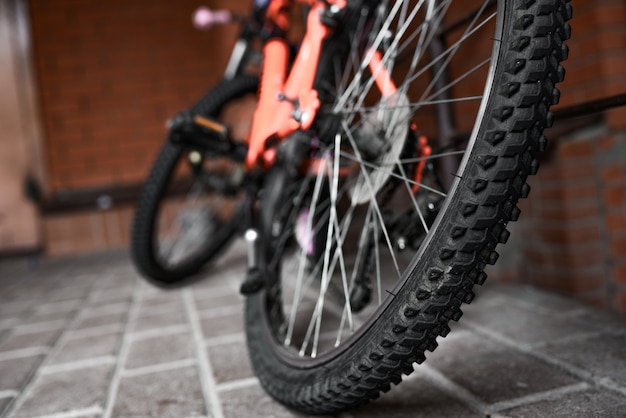 bicicleta laranja estacionada perto da parede de tijolo vermelho.