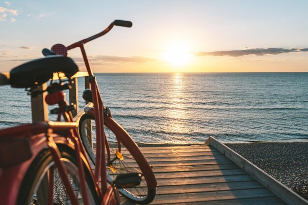 Foto bicicleta por el mar contra el cielo durante la puesta de sol