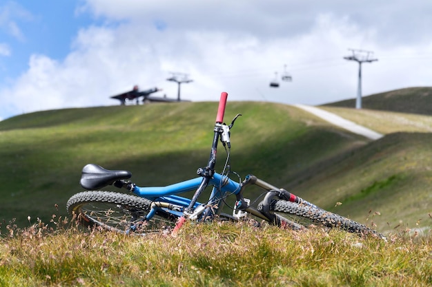 Bicicleta de montaña cuesta abajo de suspensión total tumbada en el suelo montañas sobre Livigno con teleférico en procedencia día soleado de verano Italia