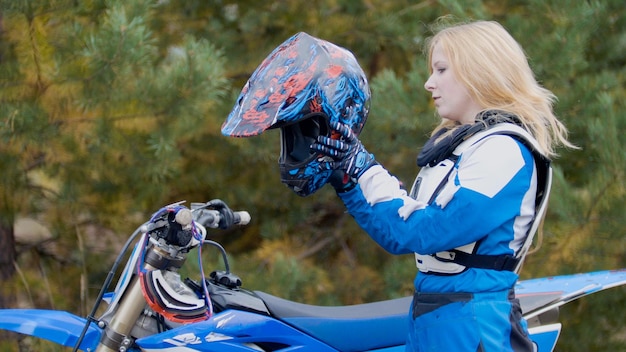 Bicicleta de niña rubia lleva un casco mx moto cross racing rider en una motocicleta de tierra