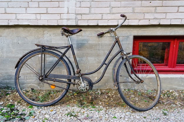 Bicicleta oxidada vieja estacionada en la pared de un edificio antiguo.