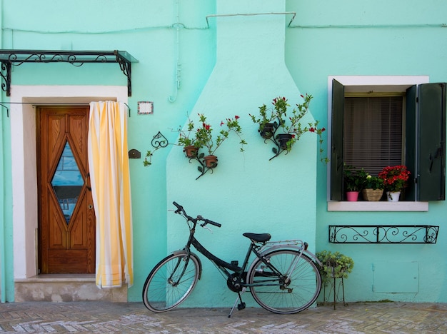 Bicicleta perto de casa turquesa na ilha veneziana de Burano, Itália