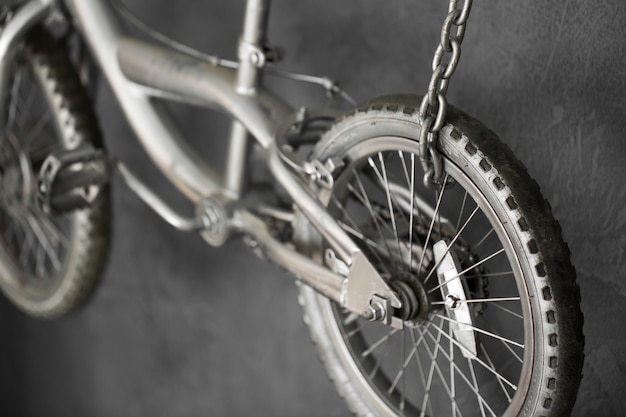 Bicicleta de plata colgando de cadenas contra la pared en el estudio