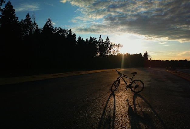 Bicicleta durante la puesta de sol en el telón de fondo de la carretera rural