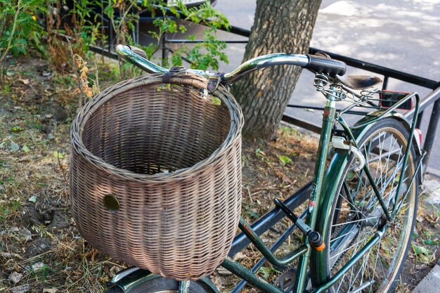 Bicicleta retrô vintage verde elegante com cesta de vime estacionada no guidão da bicicleta da cidade