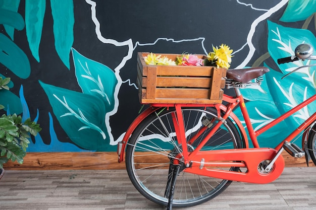 Bicicleta roja vintage con flor en cesta de madera