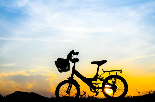 Foto bicicleta de silueta contra el cielo naranja durante la puesta de sol