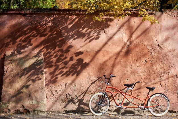 Bicicleta tándem naranja cerca de una antigua muralla