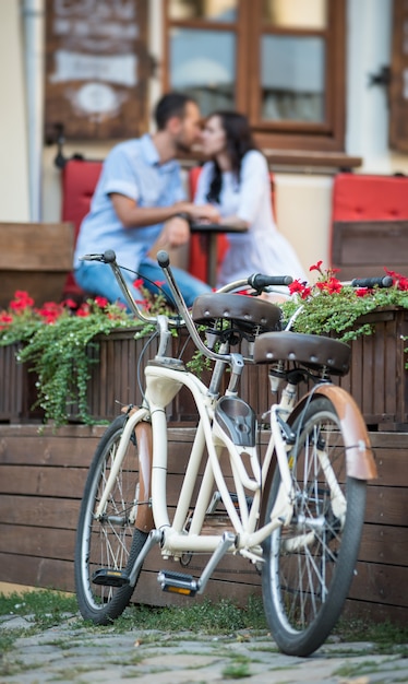 Bicicleta tándem retro cerca de flores rojas. pareja besándose