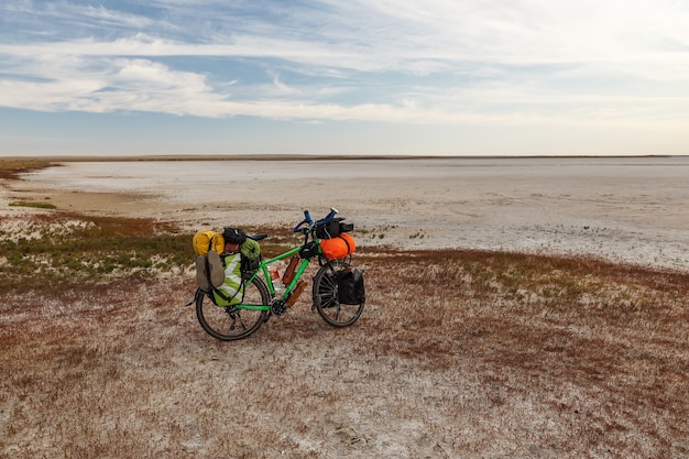 Foto bicicleta turística com bolsas fica na margem de um lago seco de sal nas estepes do cazaquistão