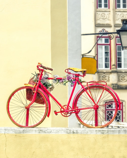 Bicicleta vermelha velha vintage decorada com flores e uma cesta.