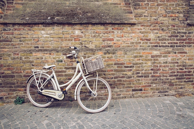 Bicicleta vintage blanca parada frente a una pared de ladrillos en la ciudad de Brujas Bélgica