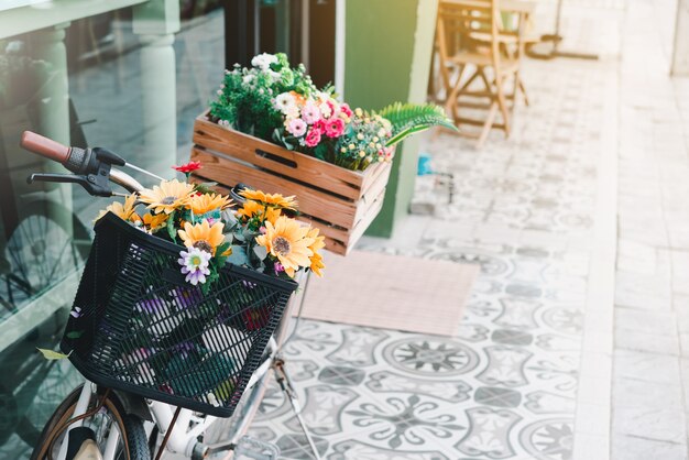 Bicicleta vintage com flores no pé de verão na rua. Bicicleta com cesta