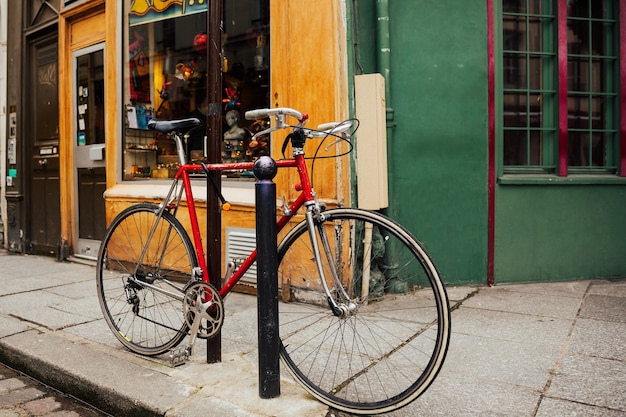 Bicicleta vintage vermelha estacionada na rua da cidade. cena urbana.