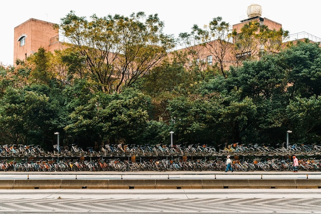 bicicletários na calçada em frente à Universidade Nacional de Taiwan com pessoas caminhando