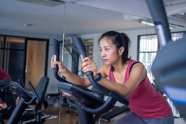 Bicicletas eléctricas de mujer en el gimnasio. Mujer joven entrenamiento en gimnasio estilo de vida saludable