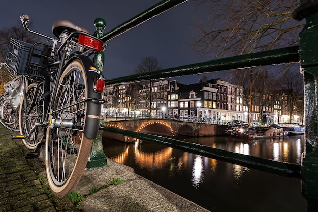 Foto bicicletas na ponte sobre o rio na cidade à noite