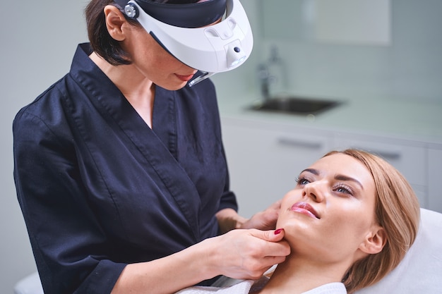 Bien hecho. Bonita chica rubia visitando un salón de belleza mientras va a hacer mesoterapia