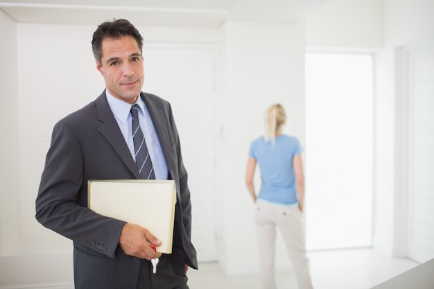 Foto bien vestido agente inmobiliario con mujer borrosa en el fondo