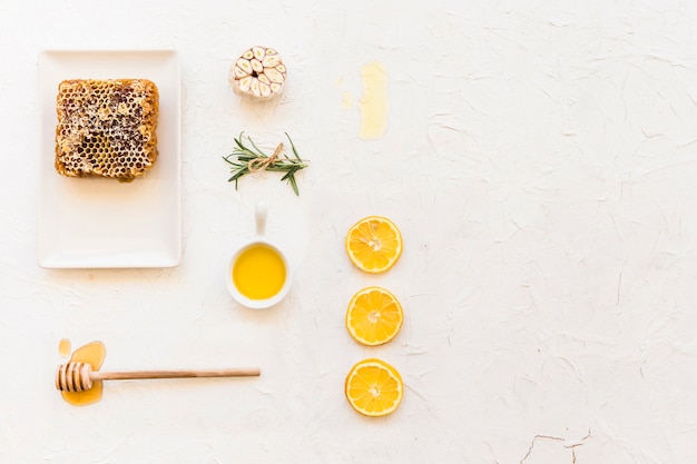 Bienenwabe mit Zitrone, Rosmarin und Knoblauch auf weißem Wandhintergrund