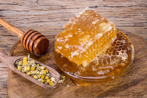 Bienenwaben und Honiglöffel auf einem hölzernen Brett und einer Tabelle