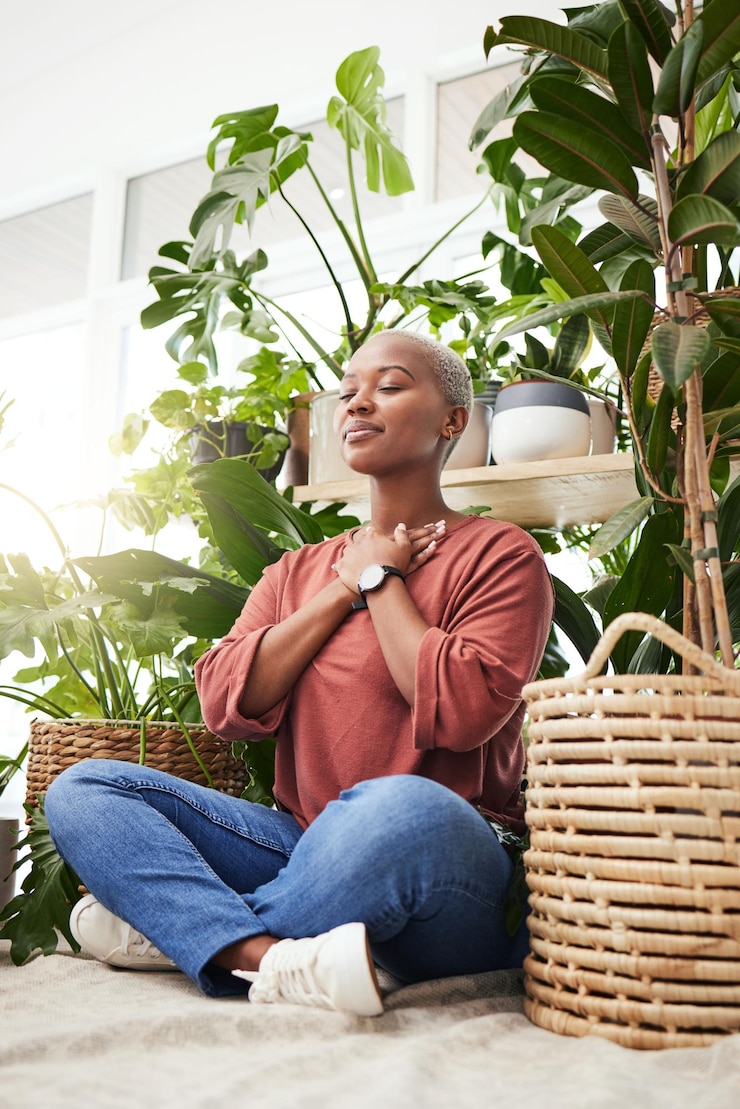 Foto bienestar paz y mujer respirando por las plantas para la meditación en un invernadero natural respirar gratitud y una joven africana tranquila con una mentalidad zen relajante junto a un vivero interior