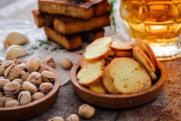 Bier in einem Glas, in Pistazien, in Roggencroutons und in Crackern auf einem Holztisch