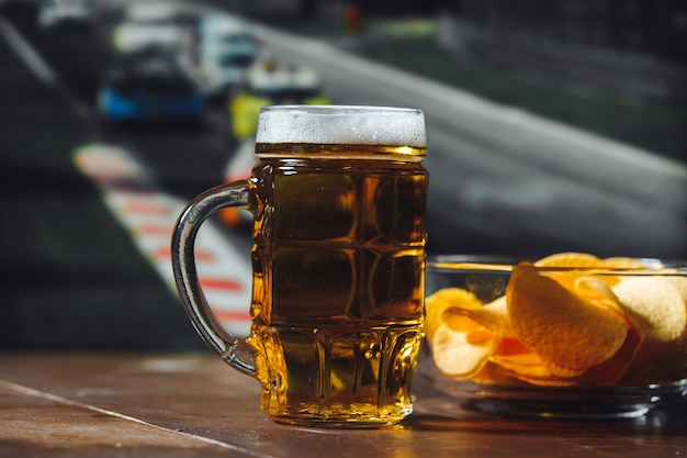 Bier mit Snack auf einem Holztisch gegen Formel-1-Rennhintergrund-Sport- und Unterhaltungskonzept