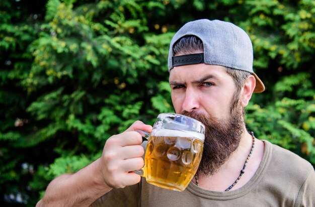 Bier und Bier Konzept Mann entspannend Bier genießen heißen Sommertag Durst löschen Alkoholgetränk und Bar Hipster brutal bärtiger Mann halten Tasse kaltes frisches Bier Craft Bier ist jung urban und modisch