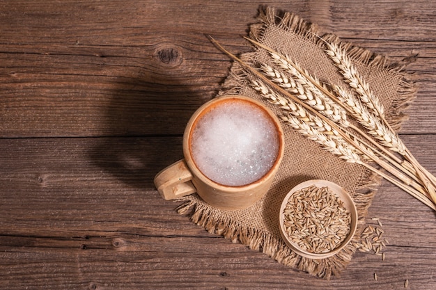 Bier und Getreide. Oktoberfest-Konzept, Holzbecher, Hintergrund der alten Bretter, Ansicht von oben