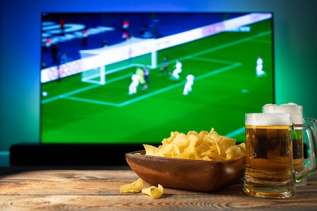 Bier und Snacks auf Fußballspiel-TV-Hintergrund