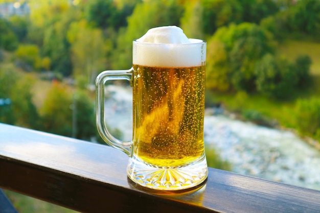 Bier vom Fass auf dem Balkongeländer mit verschwommenem Waldblick