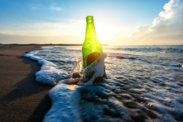 Bierflasche an einem Sandstrand mit klarem Himmel und Welle