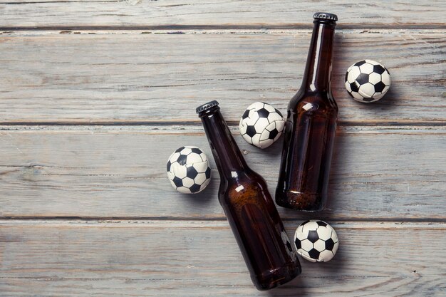 Bierflasche mit Fußballbällen auf Holzhintergrund