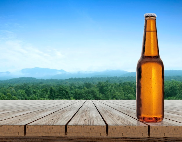 Bierflasche mit Wassertropfen auf Holztischterrasse mit erfrischender Atmosphäre in der morgendlichen Naturlandschaft
