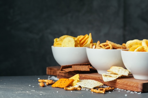 Biersnacks auf Steintisch. Verschiedene Cracker, Kartoffelchips. Ansicht von oben