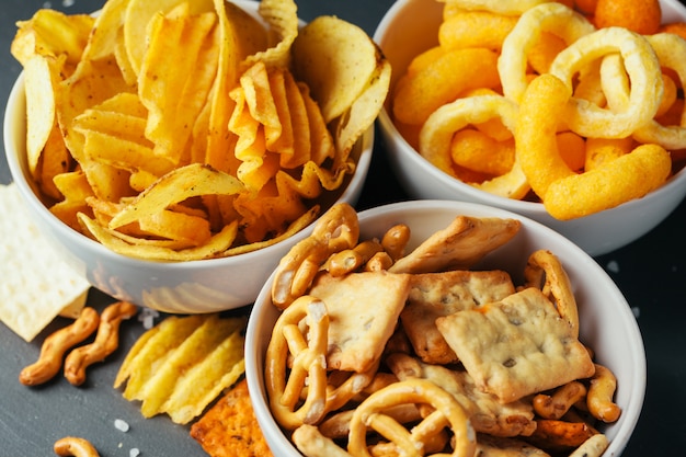 Biersnacks auf Steintisch. Verschiedene Cracker, Kartoffelchips. Ansicht von oben