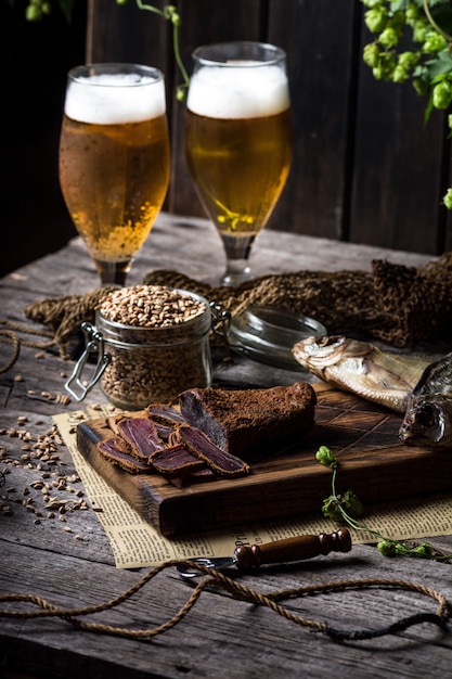 Bierstillleben mit Fischen und Flaschen. Fleisch Basturma. Oktoberfest. Trockener Fisch und trockenes Fleisch. Land Mahlzeit