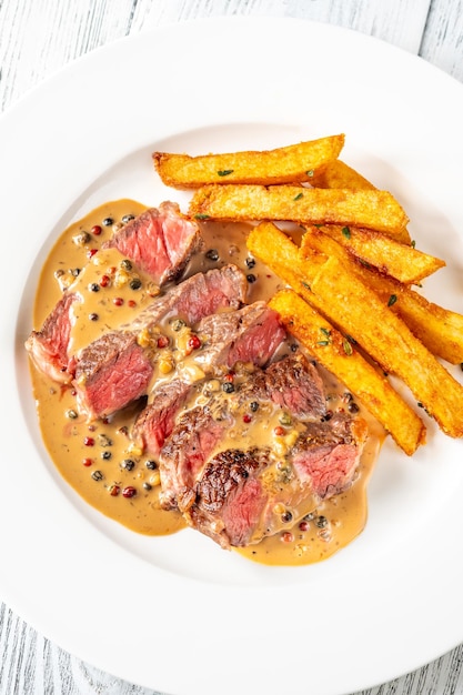 Foto bife au poivre bife francês com molho de pimenta com batatas fritas