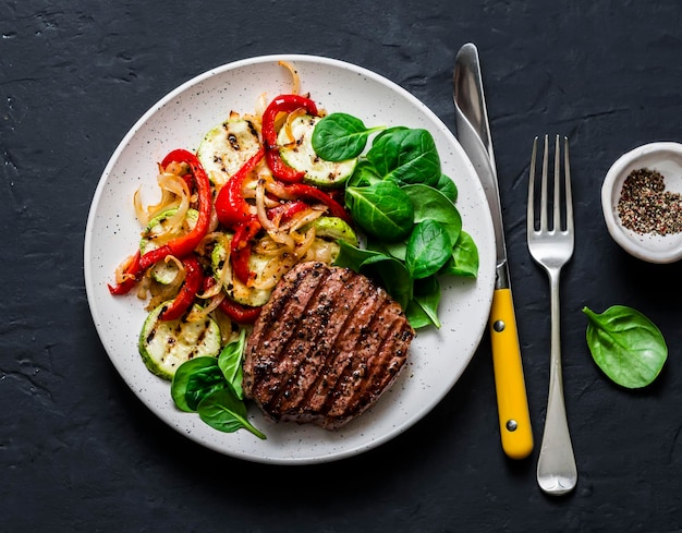 Bife com abobrinha de pimentão de legumes grelhados e espinafre fresco em um fundo escuro