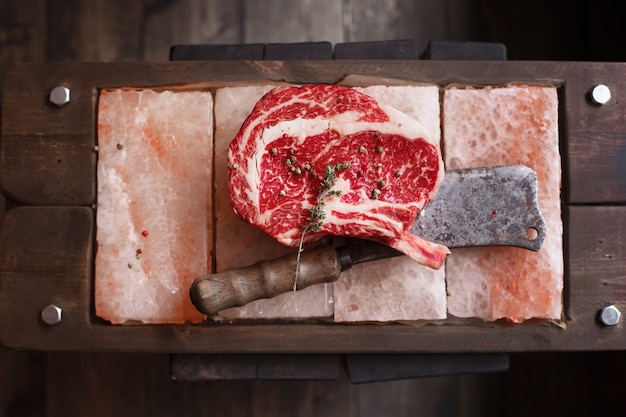 Bife com filé de costela em pedaços de sal sobre uma tábua de madeira. Imagem de estoque