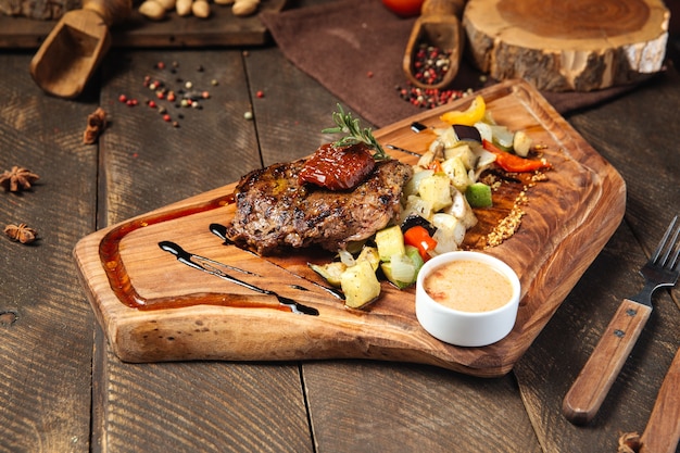 bife com legumes na tábua de madeira