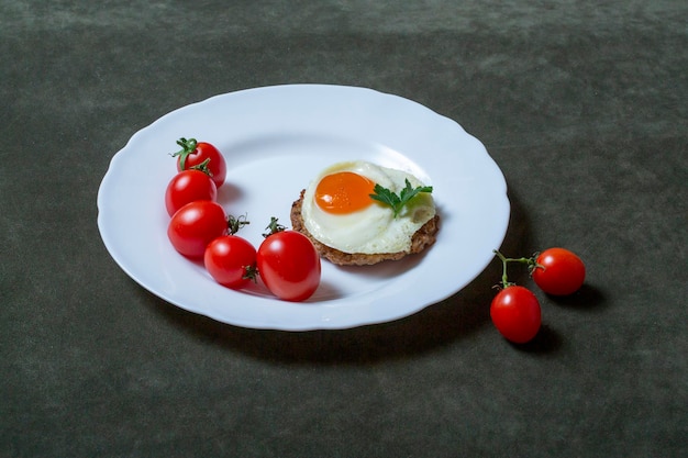 Bife com ovo e tomate em um prato branco