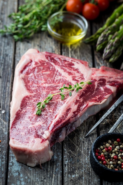 Bife cru com ervas frescas e óleo no fundo escuro de madeira