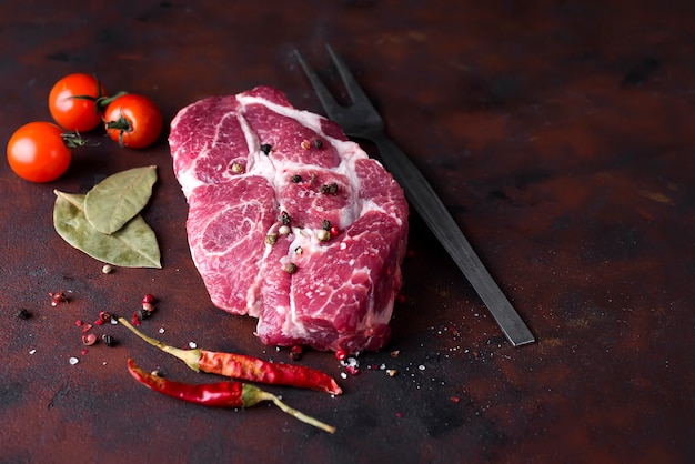 Bife cru com especiarias e ingredientes para cozinhar.