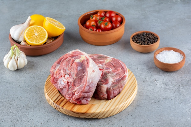 Bife cru com tomate cereja vermelho colocado numa tábua de madeira.