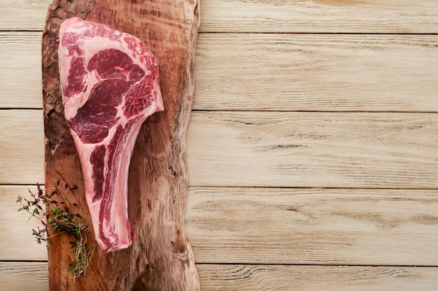 Bife cru de tomahawk fresco Bife de tomahawk cru envelhecido seco com ervas e sal no fundo de madeira velho Preparando-se para grelhar Vista superior e espaço para cópia