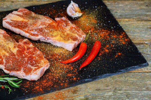 Bife da carne de porco da carne no fundo de madeira com ervas e especiarias dos ingredientes.