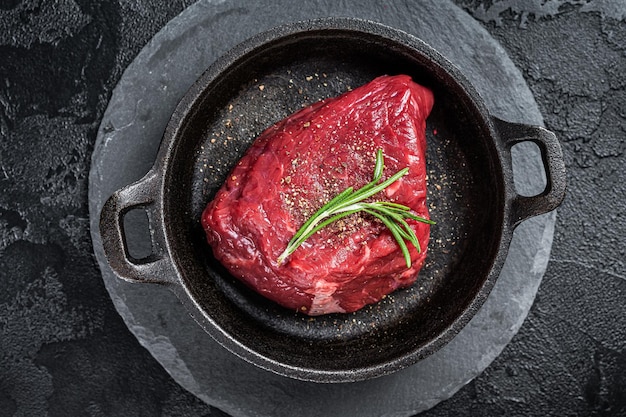 Bife de alcatra de lombo cru fresco em uma frigideira com ervas Fundo preto Vista superior